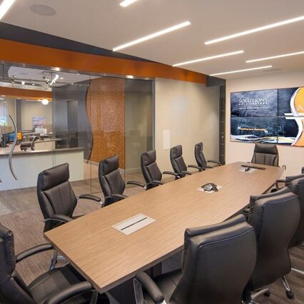 Glass meeting room with a long table and office chairs